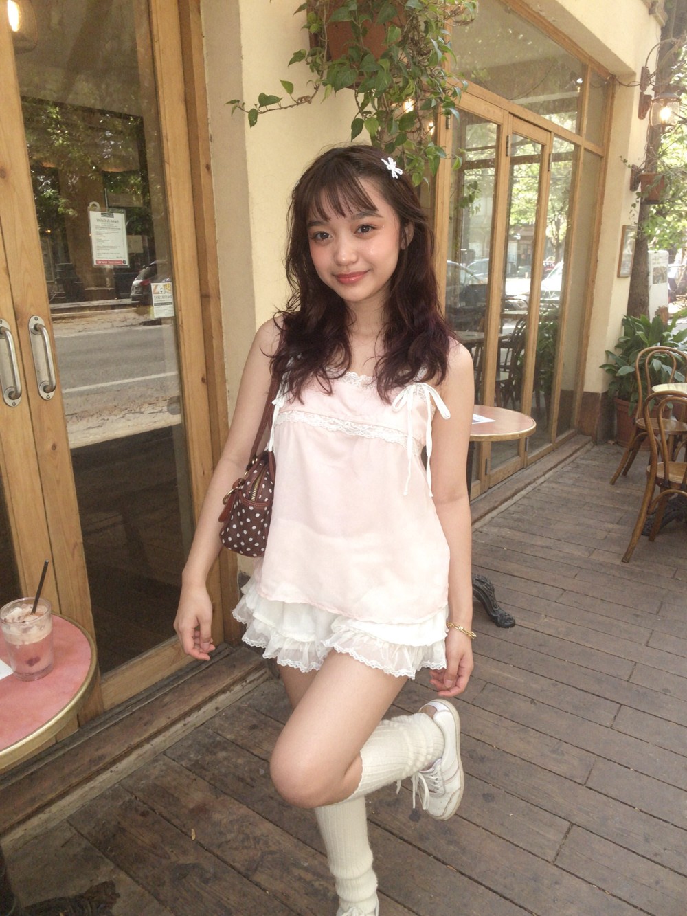The same person outside a café in a white lace outfit